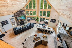 A spacious living area with a large L-shaped sofa, a dining table set for six, and a kitchen with granite countertops.