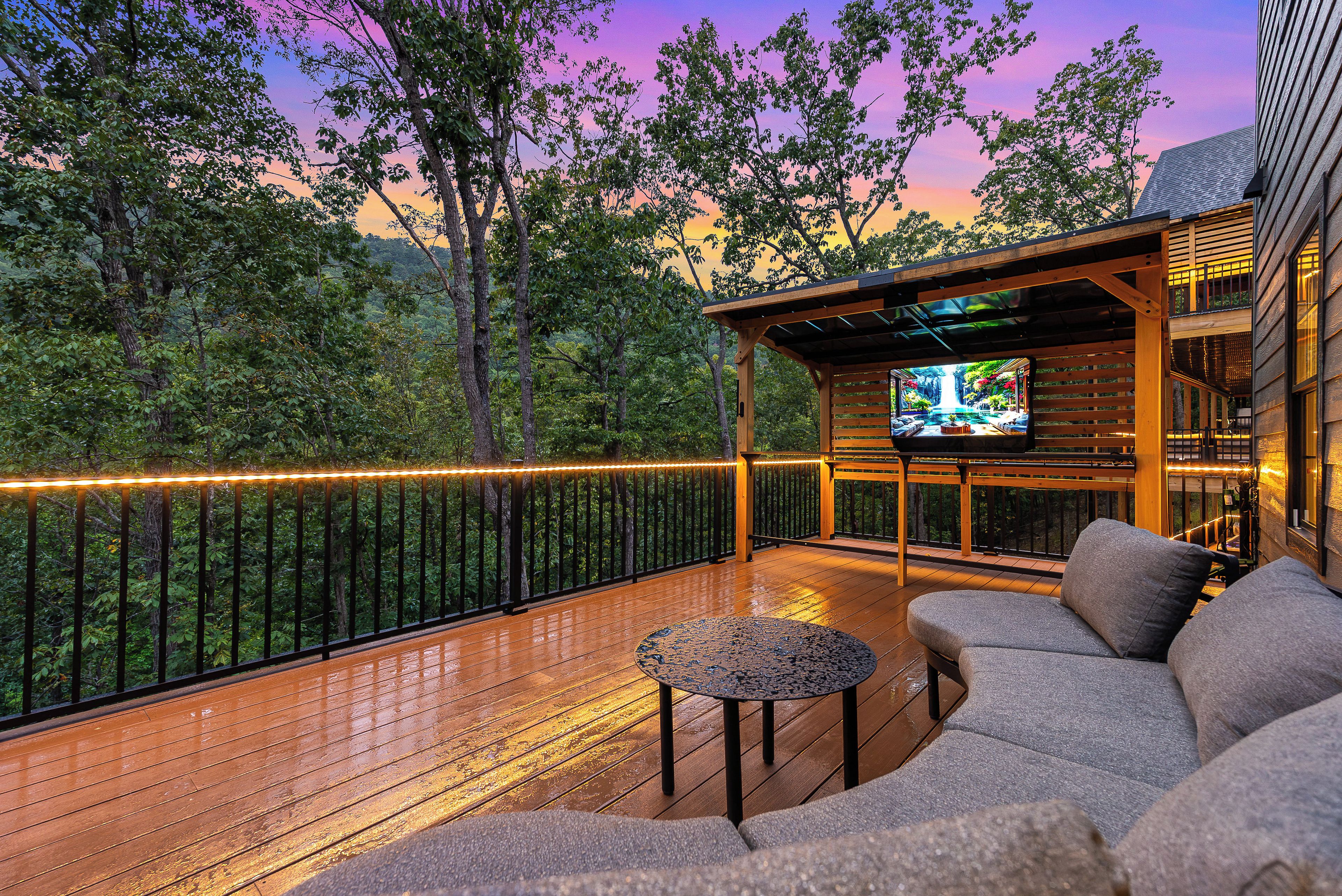 A wooden deck with outdoor seating and a TV screen.