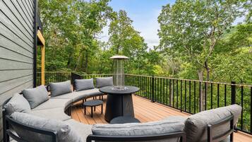 A deck with a curved sofa, a round table, and a metal railing.