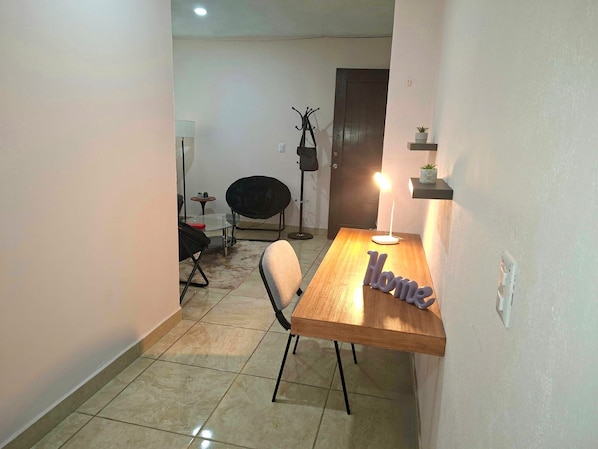 Un pequeño comedor con una mesa de madera, una silla y una lámpara.