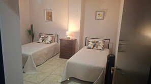 A bedroom with two beds, a nightstand, a lamp, and a door. - A1 Cuadra Historic Center New Apartment 2 Bedrooms 24/7 Parking (La Piedad de Cabadas)