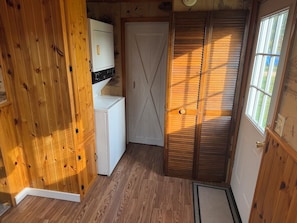 Una habitación pequeña con un armario de madera, una puerta blanca y un ventanal.