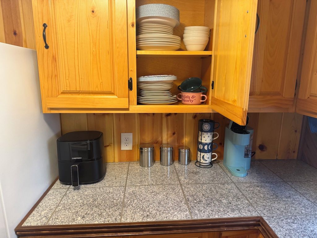 Een keuken met houten kastjes, een koffiezetapparaat en een waterkoker.