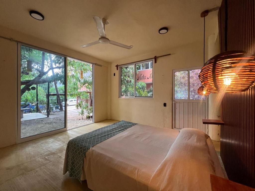 A bedroom with a bed, a ceiling fan, and a view of a garden through the window.
