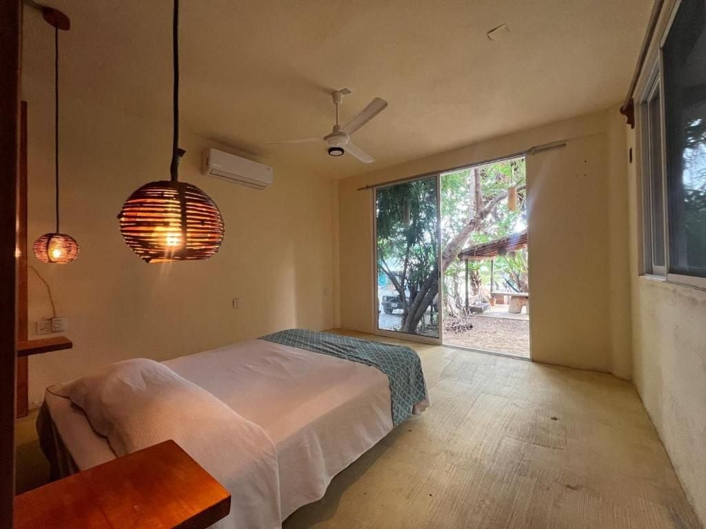 A bedroom with a bed, a ceiling fan, and a view of the outdoors.