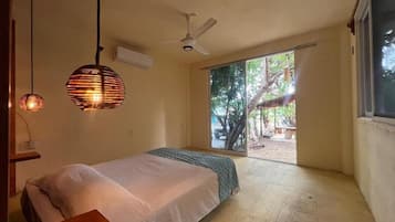 A bedroom with a bed, a ceiling fan, and a view of the outdoors.