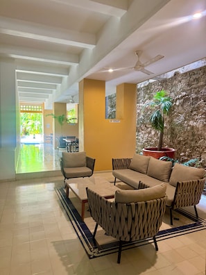 A hotel lobby with a seating area, a stone wall, and a view of the outside. - Calamari.Homes - Centenario Casa 108 - Walled City (Cartagena de Indias)