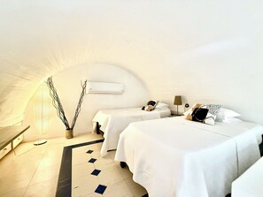 Ein schlicht eingerichteter Raum mit zwei Betten, einer Wand-Klimaanlage und einer Stehlampe.