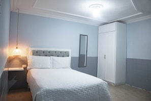 A bedroom with a bed, a nightstand, a mirror, and a wardrobe. - Big House with Yard Near the Beach - Daily Cleaning (Cartagena de Indias)
