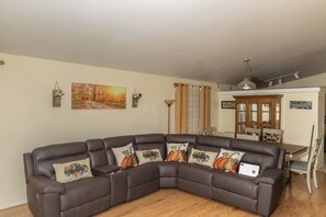A sectional sofa with decorative pillows, a dining table with chairs, a cabinet, and a painting on the wall. - 3-bedroom house in fantastic East Tucson with cool AC and comfort (Tucson)