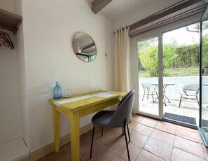 A room with a wooden desk, a chair, a round mirror, and a view of an outdoor patio with chairs and a table. - XIXTABERRI - CAMBO-LES-BAINS (CAMBO-LES-BAINS)