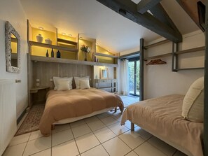 Une chambre avec deux lits, une étagère intégrée agrémentée d’objets décoratifs, un miroir et une vue à travers une porte vitrée.