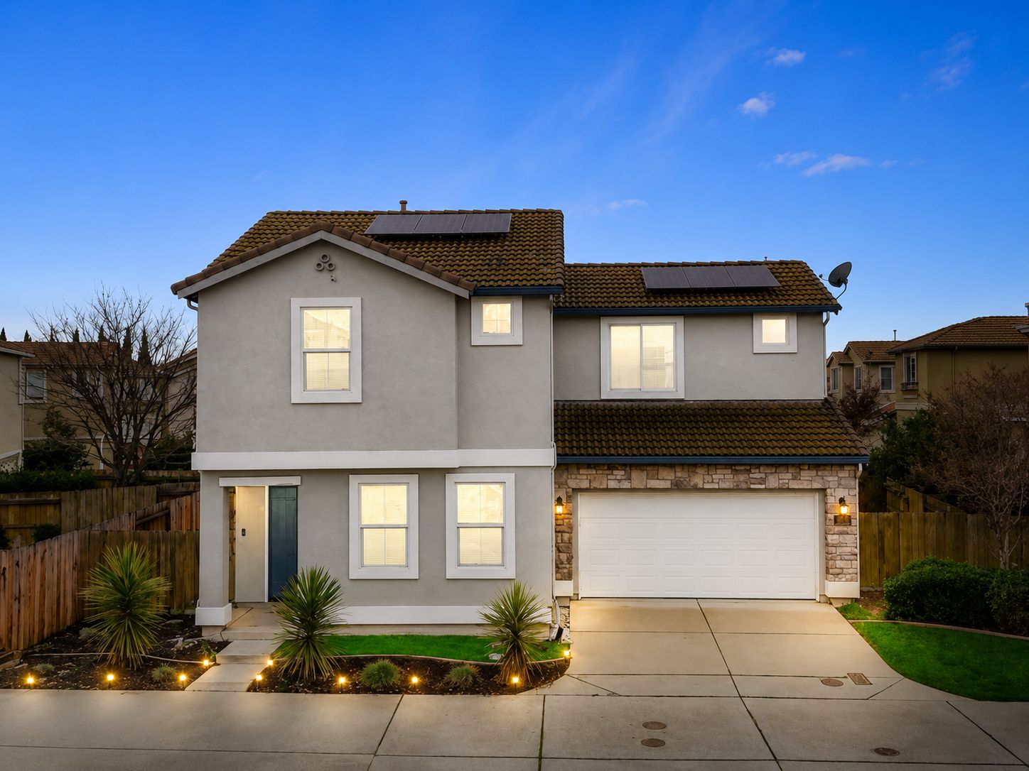 A two-story house with a garage, solar panels, and a well-maintained front yard.