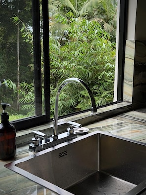Una cocina moderna con un lavamanos de acero inoxidable, un grifo y un dispensador de jabón.