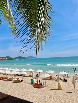 A beach with umbrellas and people. - Laika Boutique Stay (Sanya Bay) (Sanya)