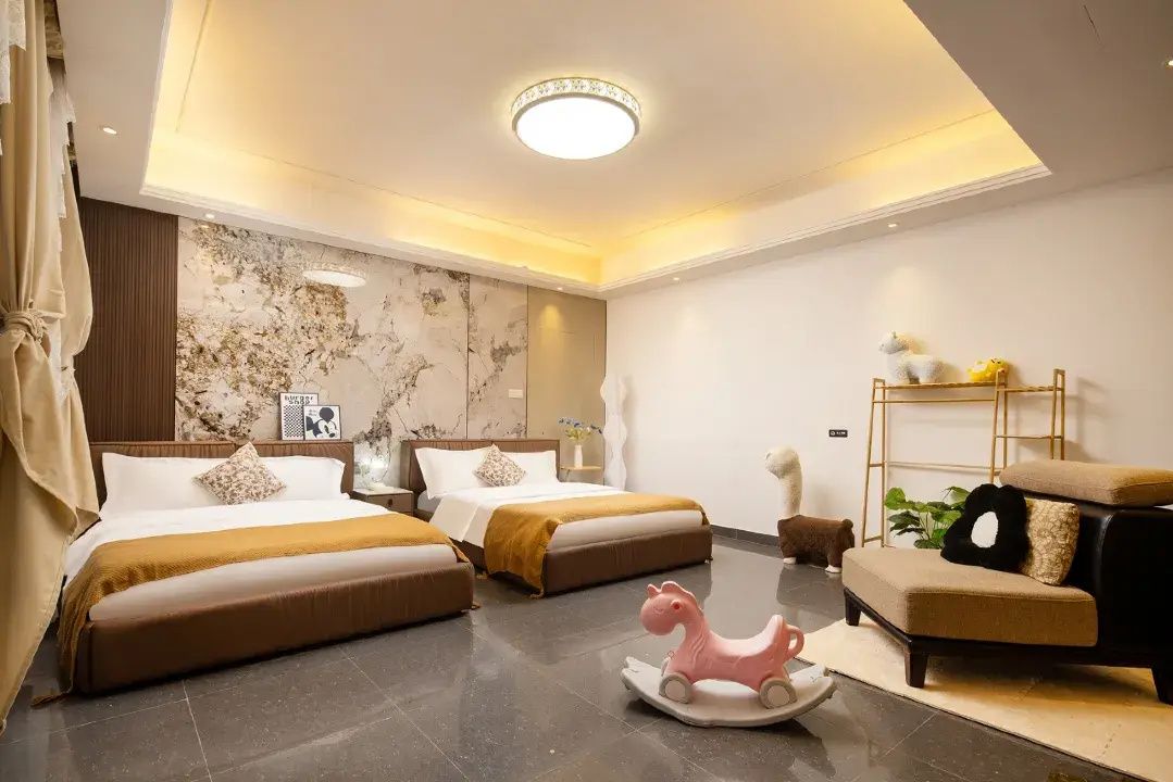 Ein Hotelzimmer mit zwei Betten, einer Couch, einer dekorativen Pferdefigur und einer Deckenleuchte.