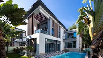 Un bâtiment moderne à deux étages, doté d’une piscine et entouré de plantes tropicales.