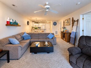 Ein Wohnzimmer mit einem Ecksofa, einem Couchtisch und einem Deckenventilator.
