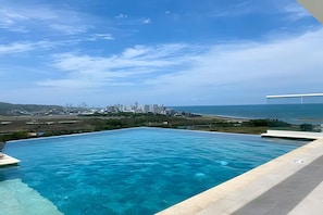 A swimming pool with a view of a city skyline and the ocean. - Modern Apartment with Private Jacuzzi and Rooftop Infinity Pool • 5-Minute Walk to the Beach (Cartagena de Indias)