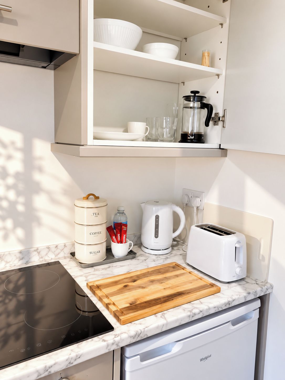 A kitchen with a built-in stove, a toaster, a kettle, and storage cabinets.