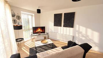 A modern living room with a fireplace, a sofa, a coffee table, and artwork on the wall.