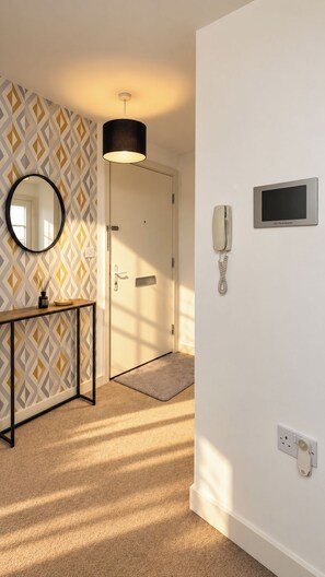 Ein Hotelzimmer mit einem strukturierten Wandteppich, einem runden Spiegel, einem Nachttisch, einer Lampe, einem Telefon und einem Fernseher.