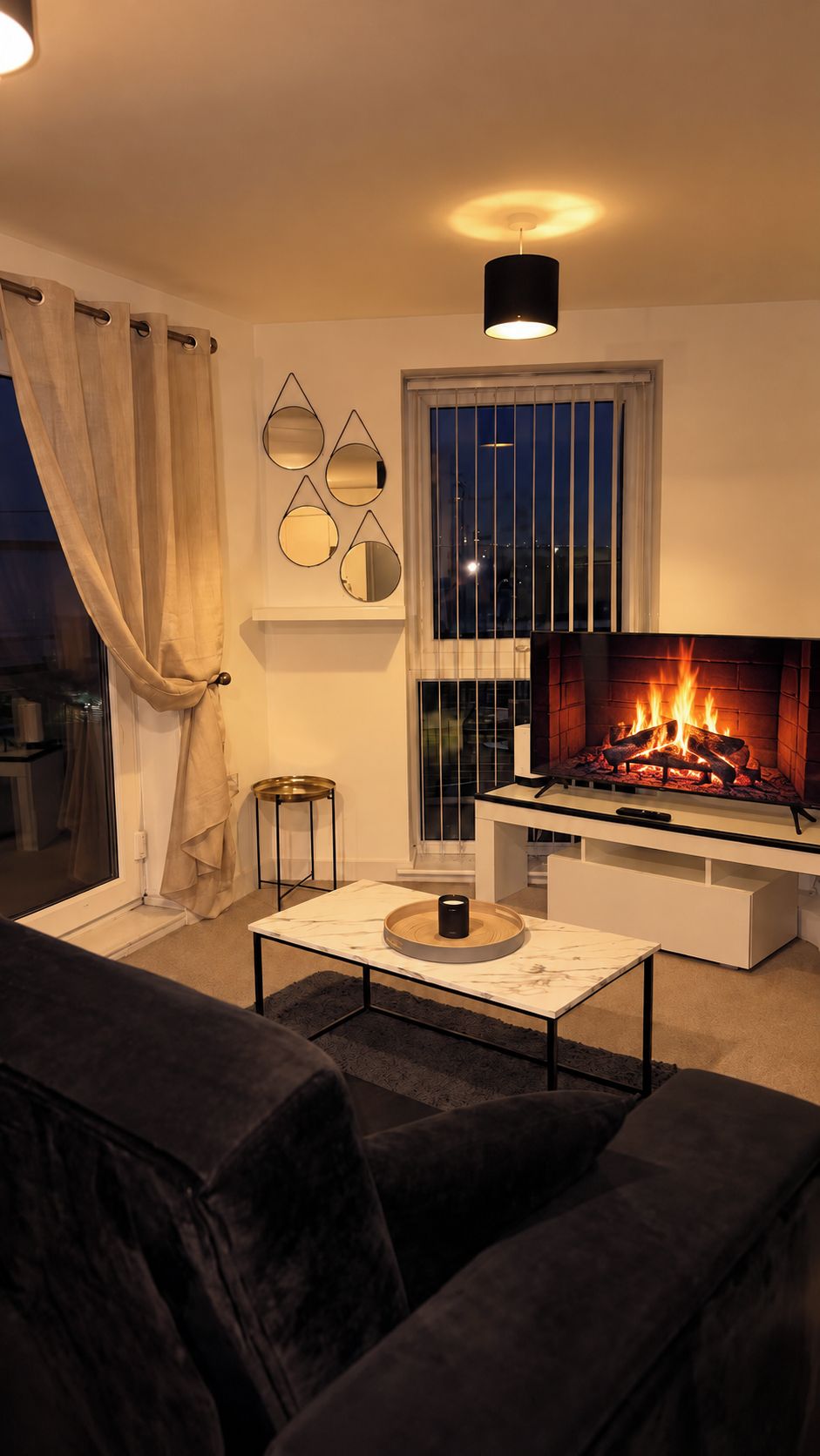 A living room with a fireplace, a sofa, a coffee table, and a window with curtains.