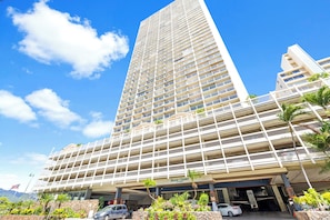 A multi-story hotel with a central atrium, outdoor parking, and a view of the surrounding landscape. - Stunning 43rd-Fl Studio with Canal Views (Honolulu)