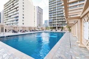 Piscina com espreguiçadeiras, rodeada por edifícios altos.