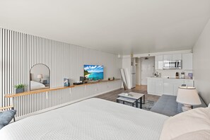 A modern hotel room with a large bed, a TV, a kitchen area, and a view of the ocean. - Stunning 43rd-Fl Studio with Canal Views (Honolulu)