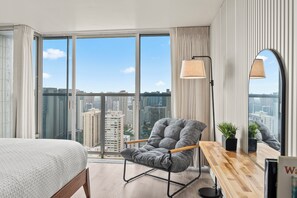 A modern hotel room with a large window, a bed, a seating area, and a desk. - Stunning 43rd-Fl Studio with Canal Views (Honolulu)