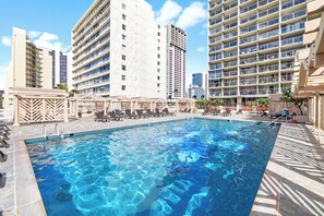 A swimming pool with lounge chairs and umbrellas, surrounded by tall buildings. - Stunning 43rd-Fl Studio with Canal Views (Honolulu)