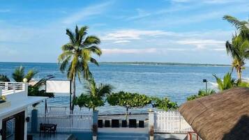 A beachfront property with a patio, palm trees, and a view of the sea.