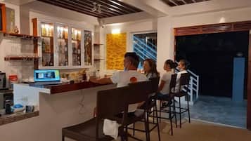 Una zona de bar con mostrador, asientos y una escalera que sube a un nivel superior.
