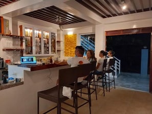 A bar area with a counter, seating, and a staircase leading to an upper level. - Maykenn Beach Resort (Bantayan)