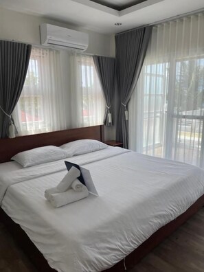 A hotel room with a large bed, curtains, an air conditioning unit, and a view of the outdoors. - Maykenn Beach Resort (Bantayan)