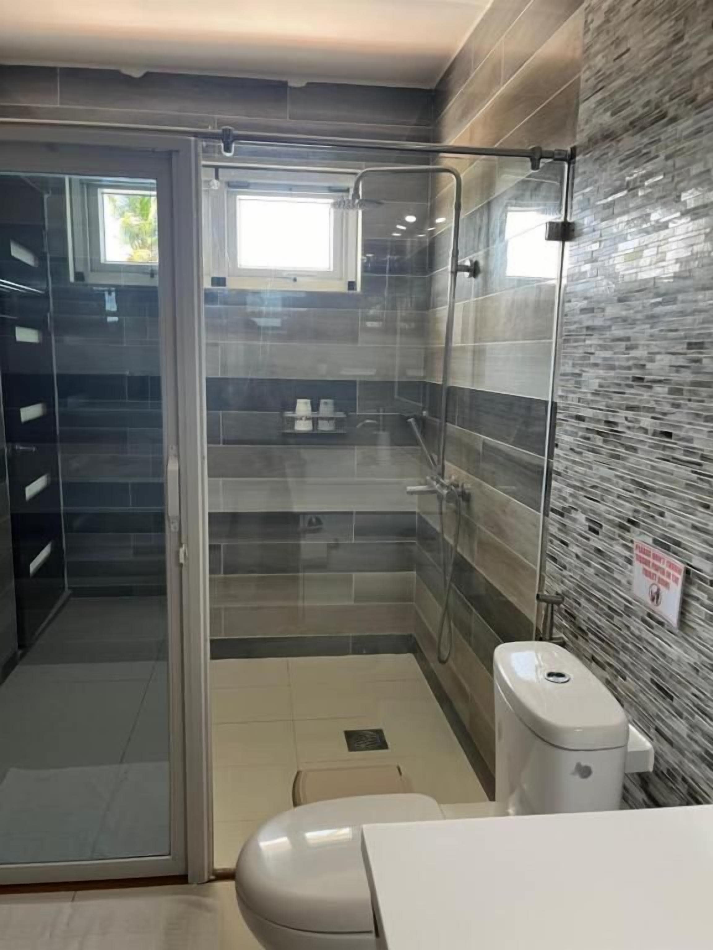 A modern bathroom with a glass shower enclosure, a toilet, and a sink.