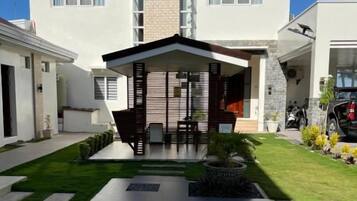 A modern two-story house with a covered patio, a driveway, and a well-maintained lawn.