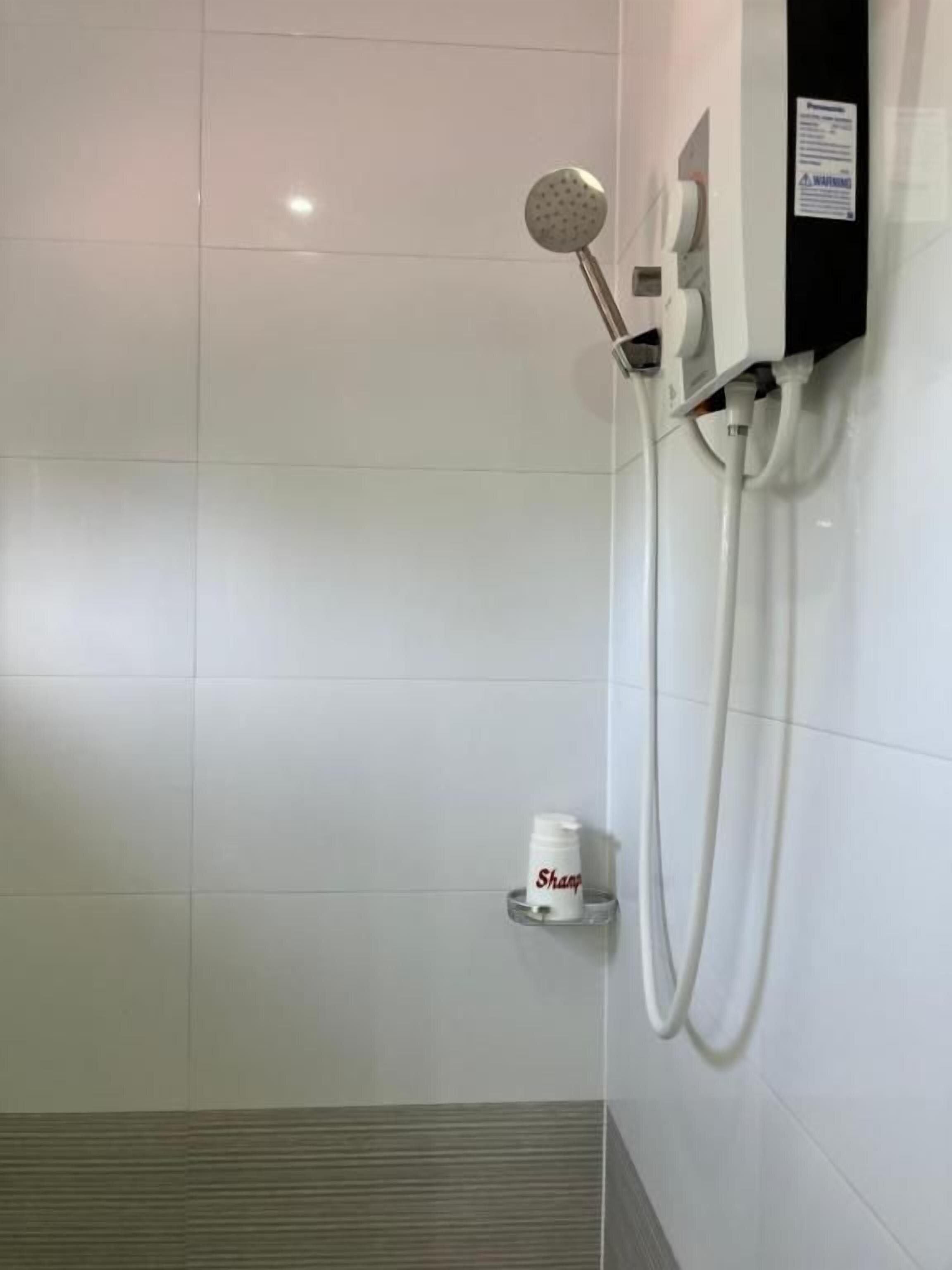 A shower area with a handheld showerhead, a soap dispenser, and a towel rack.