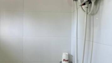 A shower area with a handheld showerhead, a soap dispenser, and a towel rack.