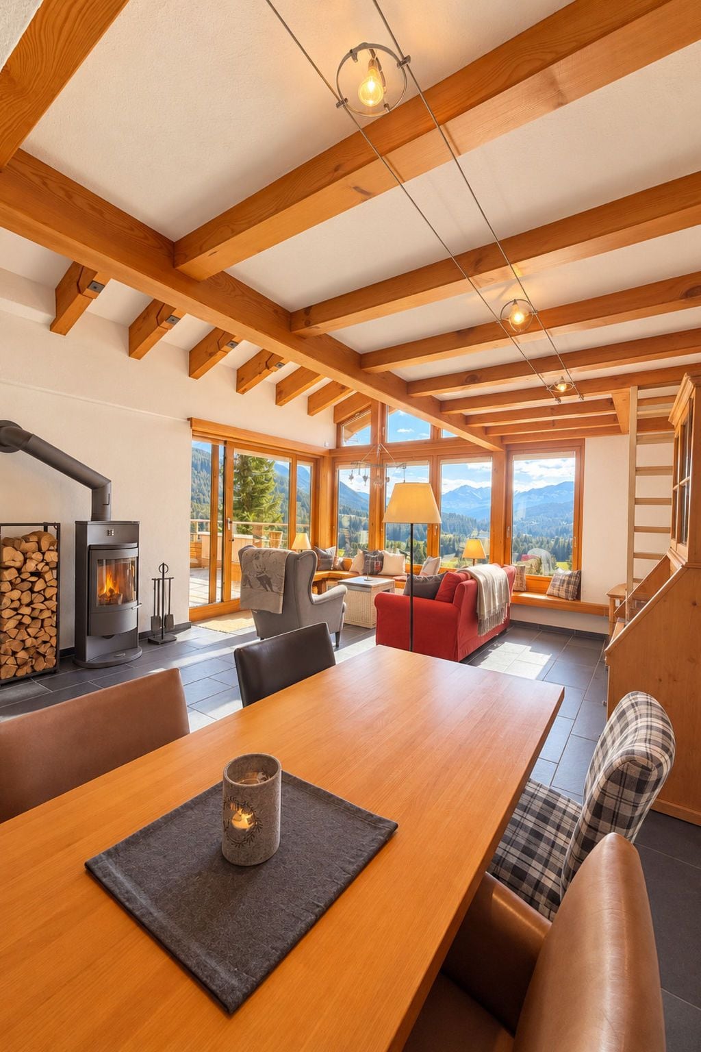 A spacious living area with a wooden ceiling, a fireplace, a dining table, and a sofa.