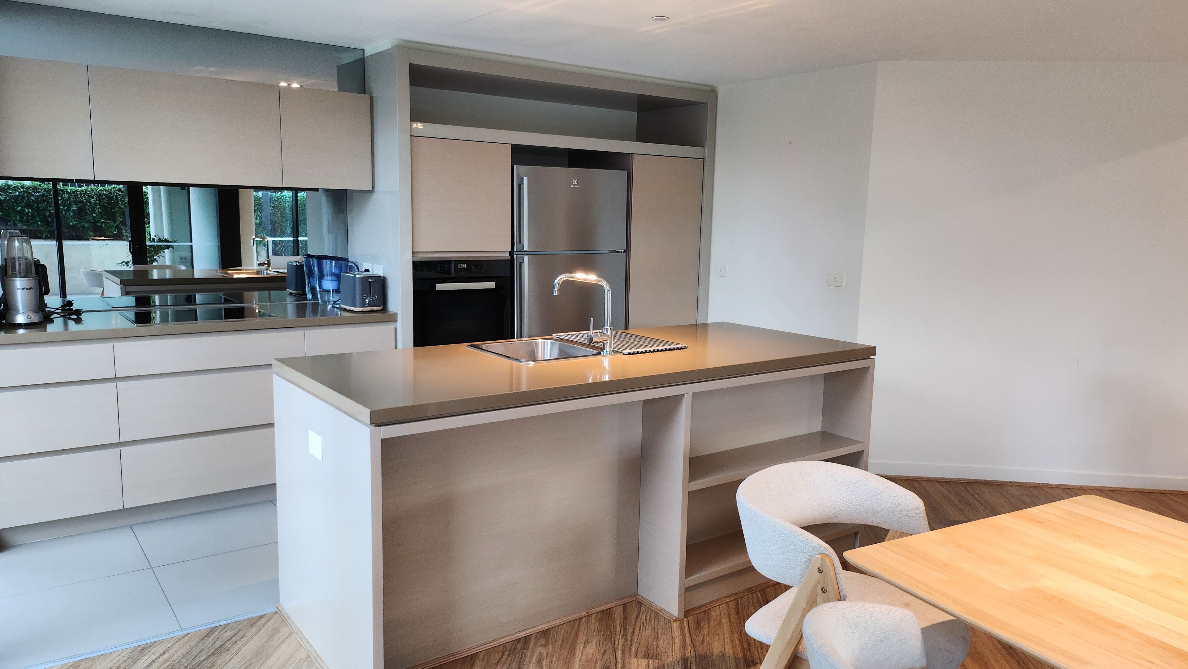 A modern kitchen with a built-in island, stainless steel appliances, and a dining area with a wooden table.