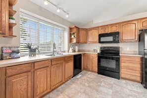 A modern kitchen with wooden cabinets, a stainless steel refrigerator, a built-in oven, and a window with blinds. - Prime Bellevue Home / Mins to Offutt AFB & Zoo (Bellevue)
