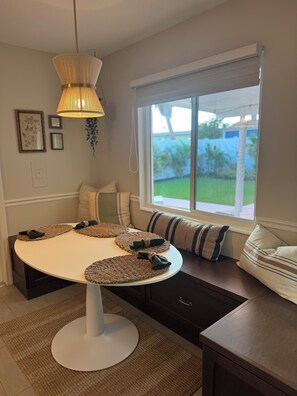 A dining area with a round table, woven placemats, and a hanging light fixture. - Chic 2-Bedroom Home with Heated Pool + Bar close to AMI/IMG (Bradenton)