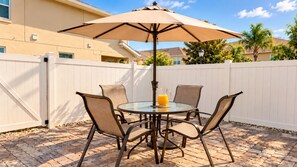 A patio with a round table, four chairs, and a large umbrella. - The Magic House, Near Disney, Game Room, 10 Guests (Kissimmee)