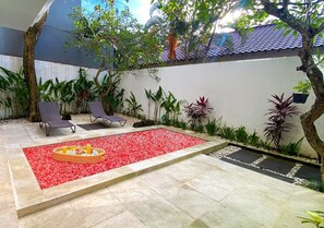 A patio area with a tiled floor, a small fire pit, and lounge chairs. - Vimana Bali Seven Managed by AVM (Badung)