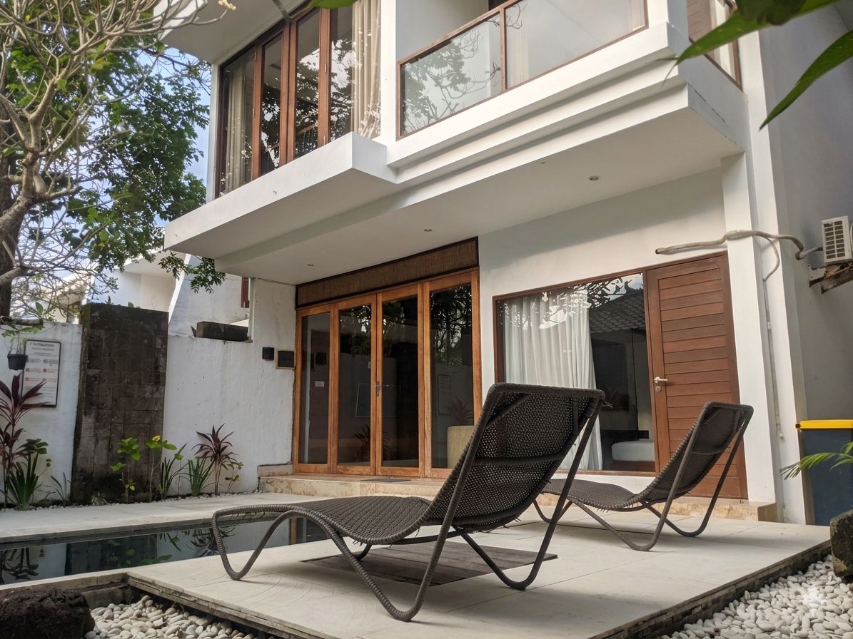 Uma casa moderna de dois andares com varanda, piscina e duas cadeiras de descanso.