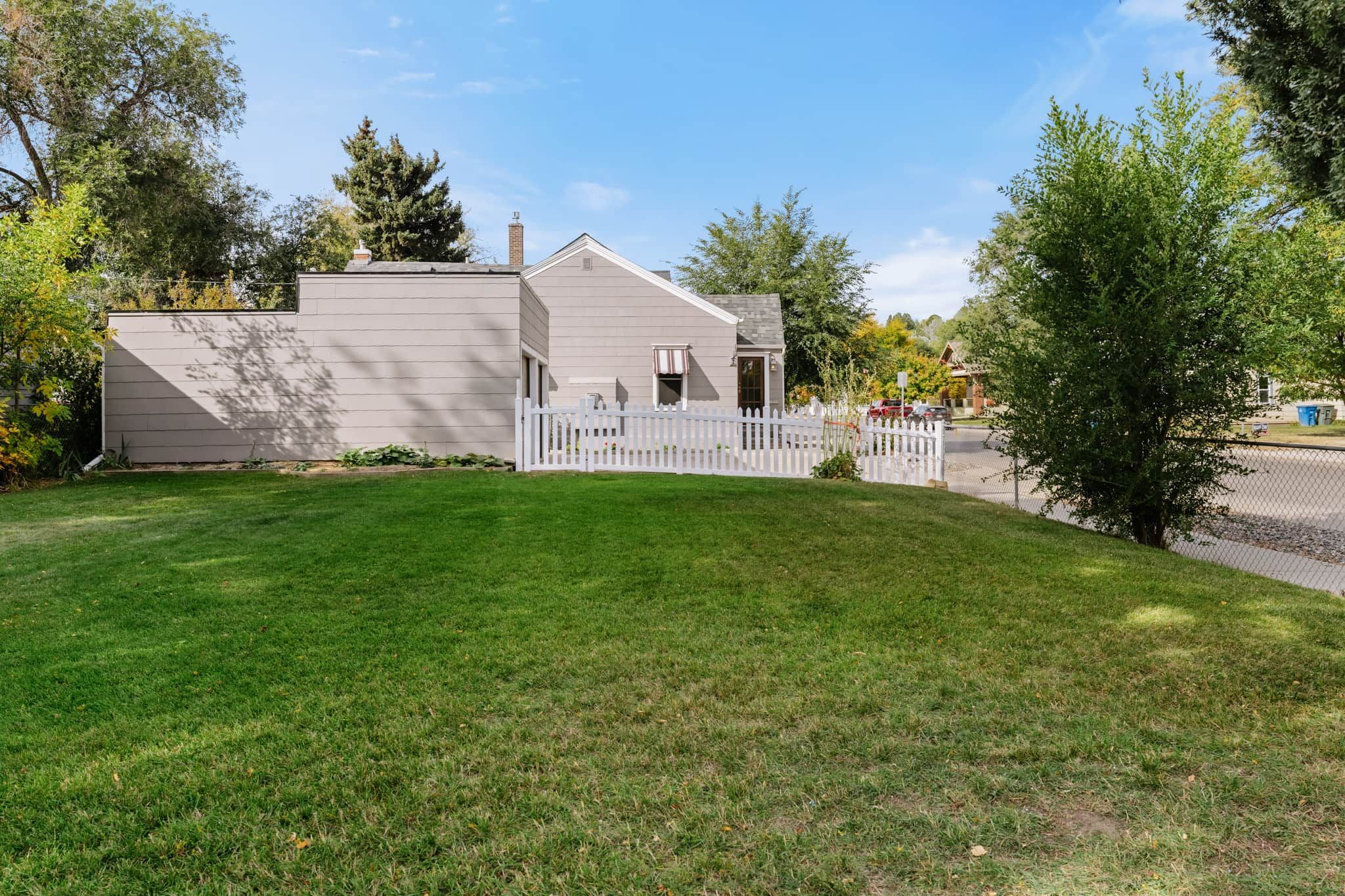 A two-story house with a white picket fence, a well-maintained lawn, and a clear sky.