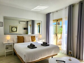 A hotel room with a large bed, two bedside tables with lamps, a round coffee table, and a view of the outdoors through a glass door. - SR Romana Playa 811, directly on the beach (Marbella)