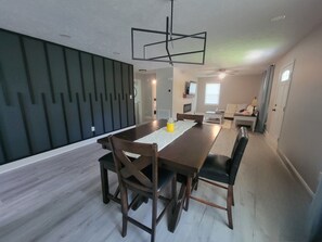 A modern dining area with a long table, chairs, and a unique ceiling light fixture. - Charming 3-bedroom house in Southern Pines (Southern Pines)